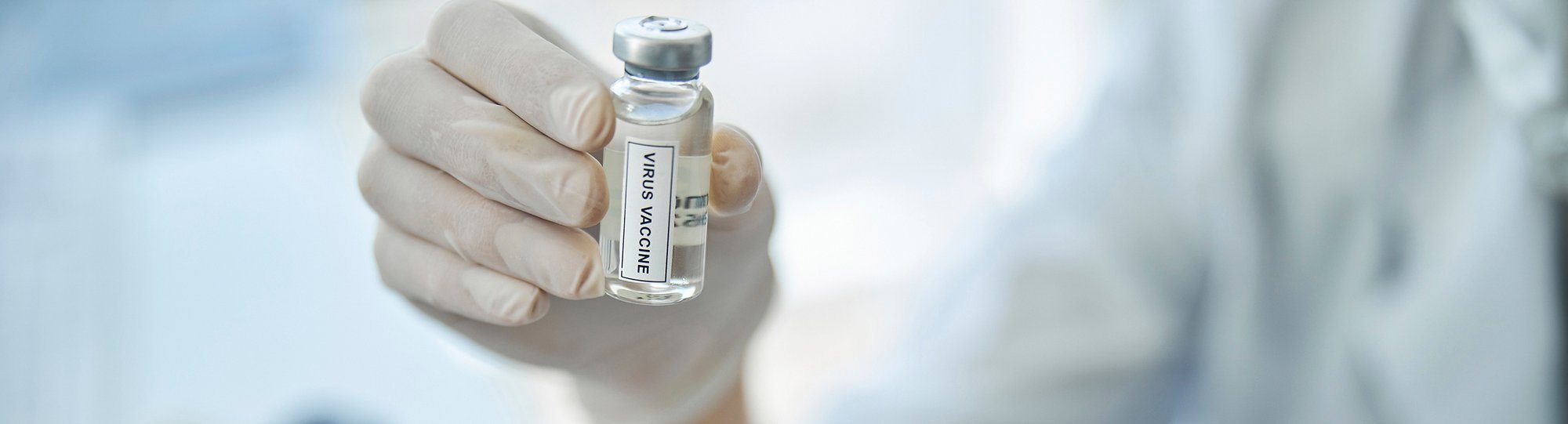 Gloved hand holding a vial of medicine