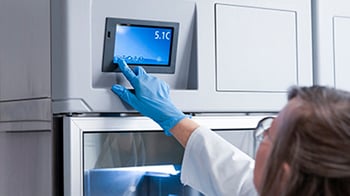 A female lab technician adjusts settings on a Follett refrgerator