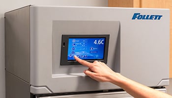 Closeup of a person pressing options on a Follett upright refrigerator control panel